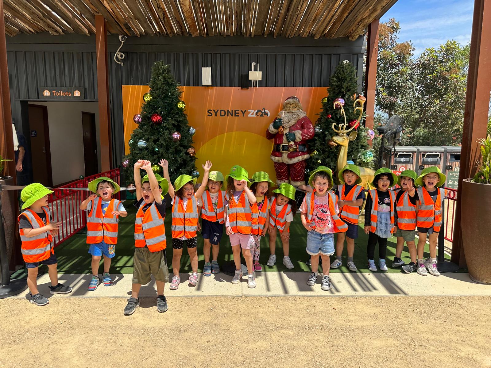 Preschool children wearing safety vests and hats posing happily during a Cuddles 4 Kids excursion field trip to Sydney Zoo